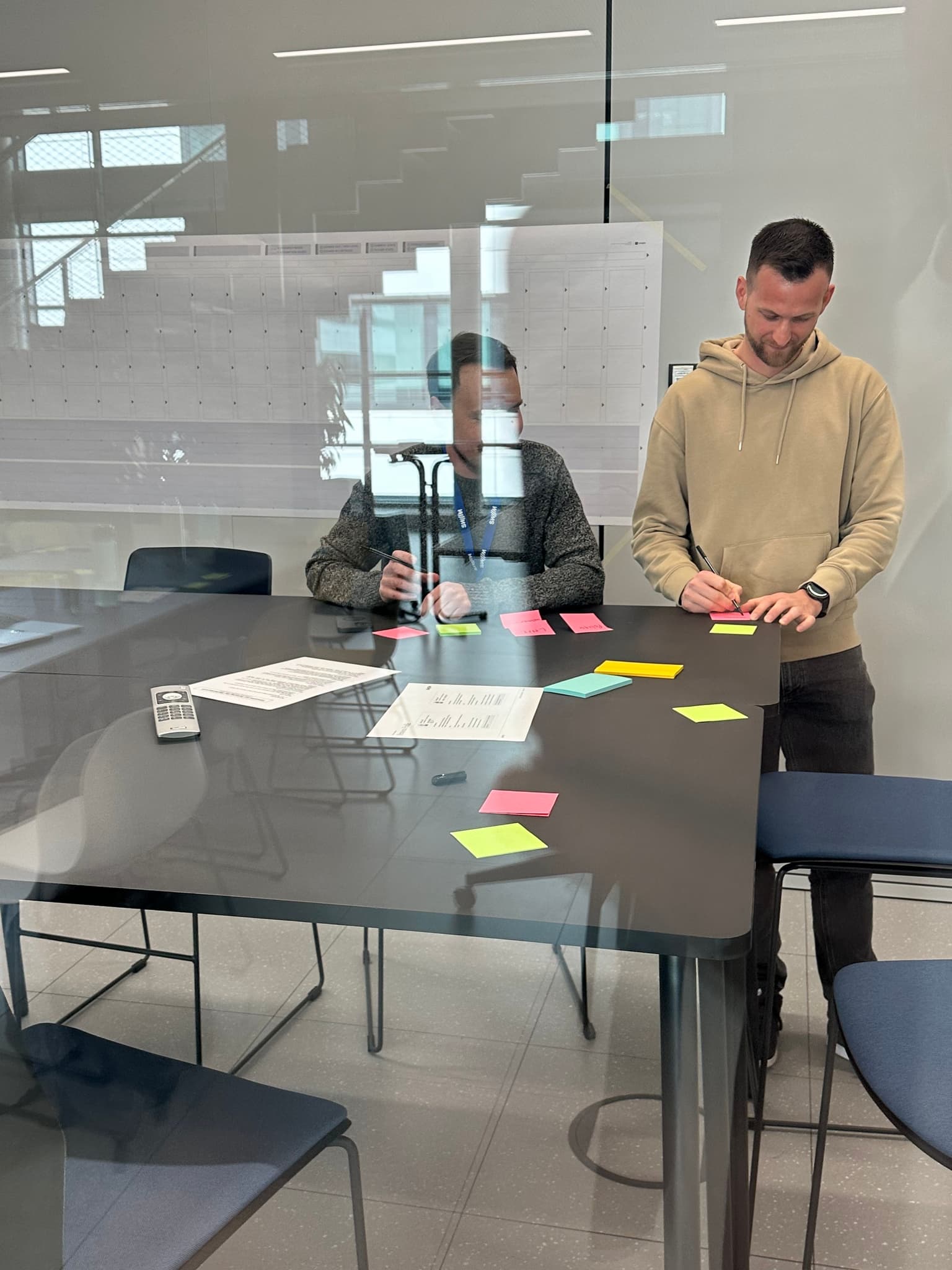 people working on a table behind a window