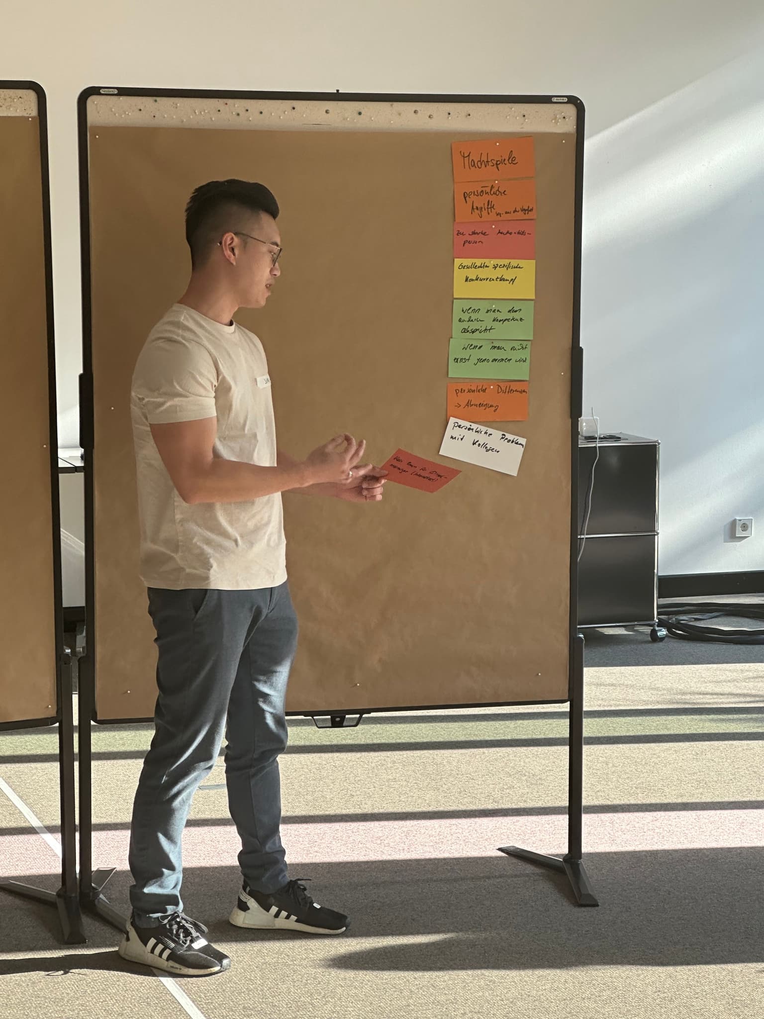 Man presenting a post-it in front of a brown wall